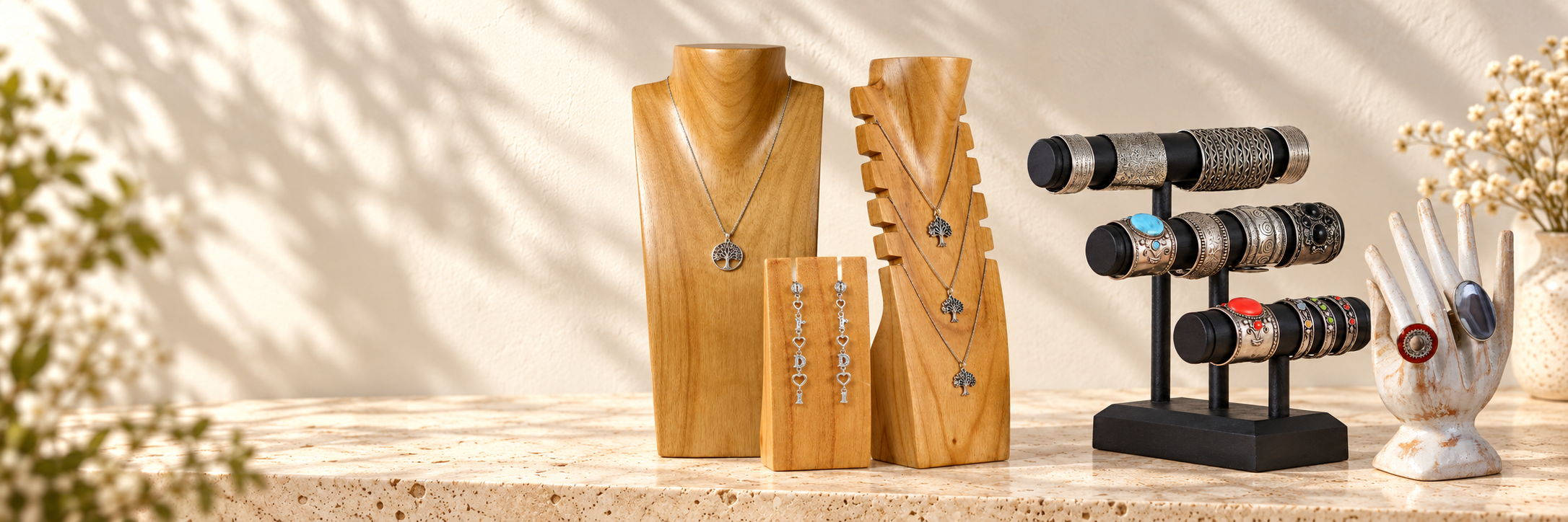 Handcrafted wooden necklace, bracelet, ring and earring displays on a warm stone counter.